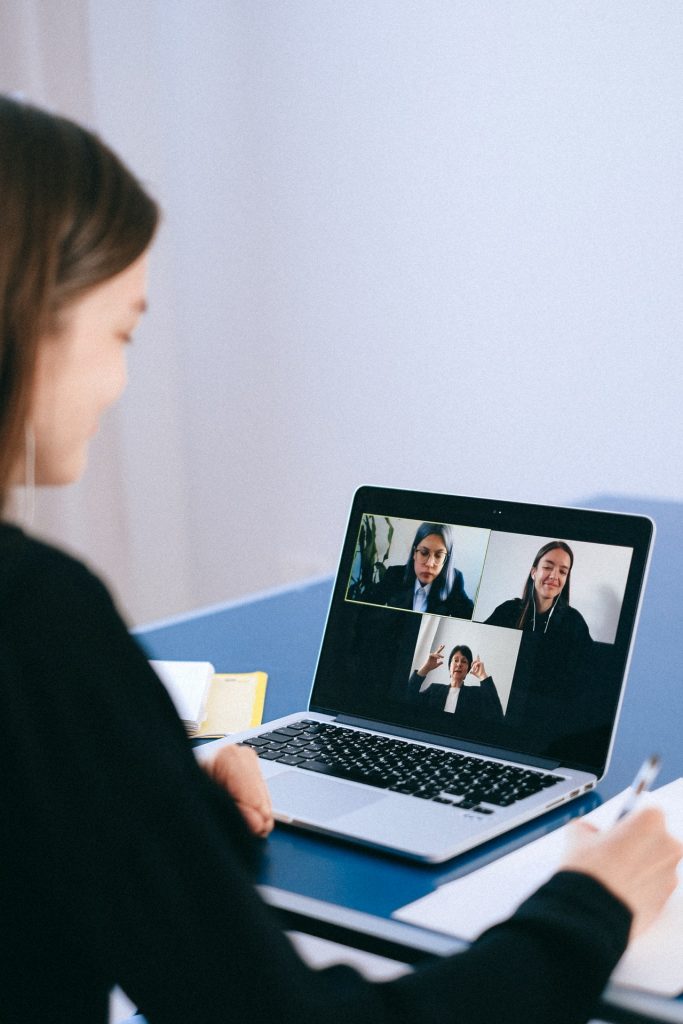 A woman communicates with other via video conferencing technology on a laptop.