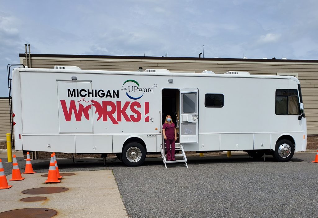A woman stands in the doorway of our mobile unit in a parking lot.