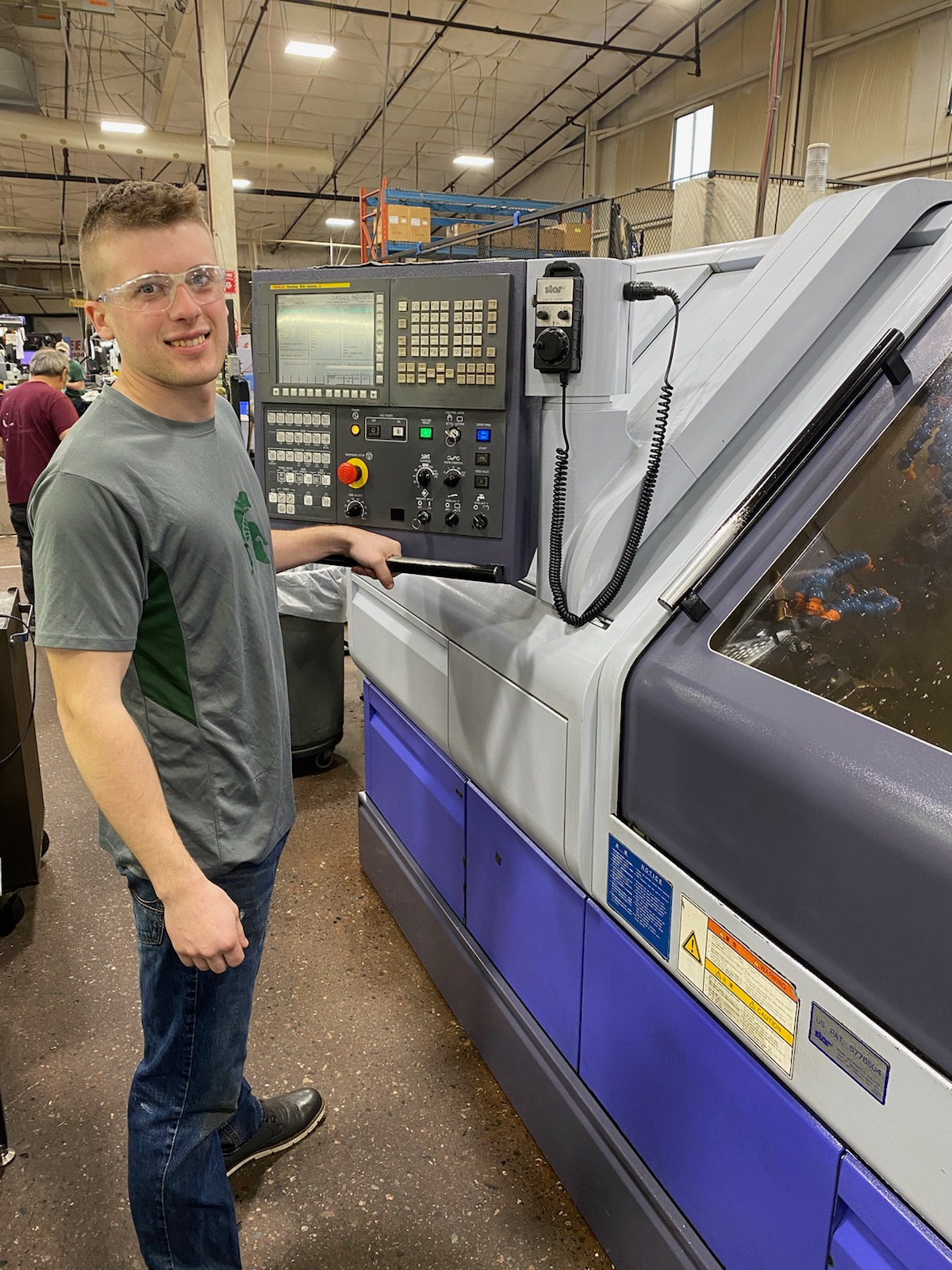 Nick stands in front of a CNC machine at work.