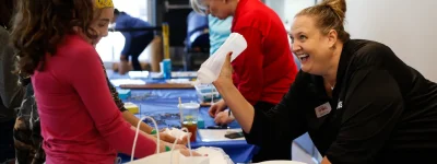 Mind Trekkers Promo Picture. Michigan Works employee leans over demonstration table to show a student how to spray water