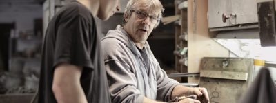 A man and a younger man work in an industrial setting.